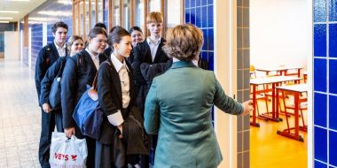 Leerlingen van het derde jaar wachten in rij aan de deur bij het begin van de les 